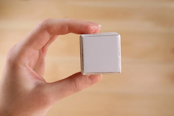 Cubo educativo in mano, su sfondo di legno — Foto Stock