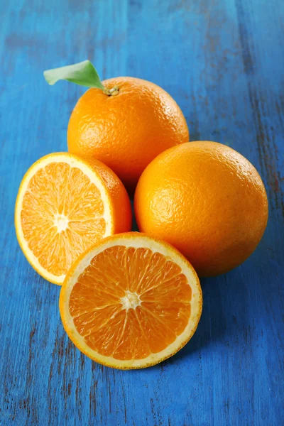 Reife Mandarinen und Orangen mit Blättern auf Holzgrund — Stockfoto