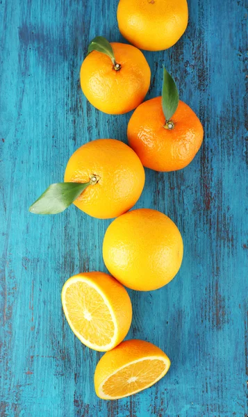 Ripe tangerines and oranges with leaves on wooden background — Stock Photo, Image