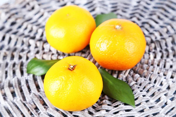 Mandarinas con hojas sobre fondo de mimbre —  Fotos de Stock