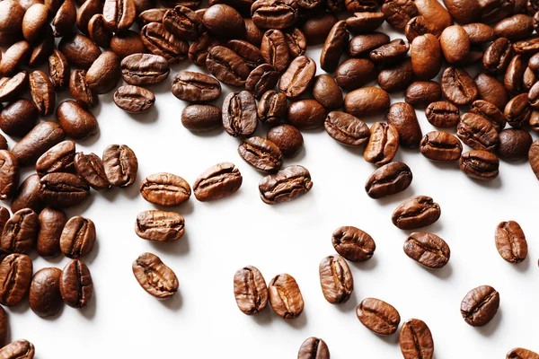 Grãos de café na mesa branca, close-up — Fotografia de Stock