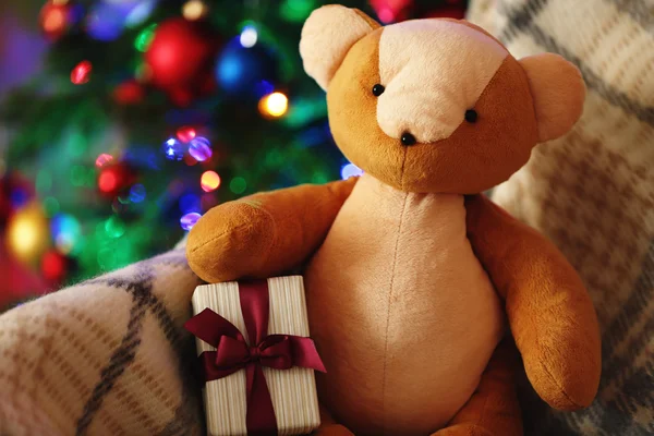 Teddybär und Geschenkschachtel im Schaukelstuhl auf Christbaumhintergrund — Stockfoto