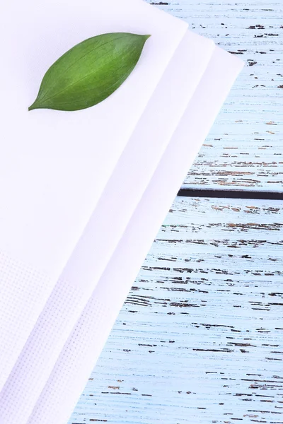 Vita servetter med gröna blad på träbord — Stockfoto