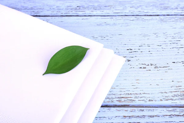 White napkins with green leaf on wooden table — Stock Photo, Image