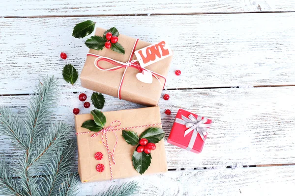 Beaux cadeaux de Noël avec houx européen (Ilex aquifolium) sur fond en bois — Photo