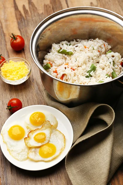 Tasty rice in pan on wooden table — Stock Photo, Image