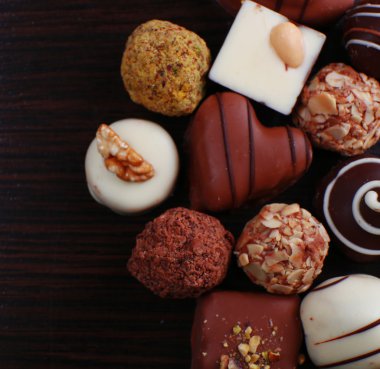 Koyu ahşap düz arka plan üzerinde çeşitli çikolatalar