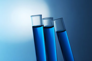 Eğimli test tüpleri gölgeler zemin üzerine mavi su ile