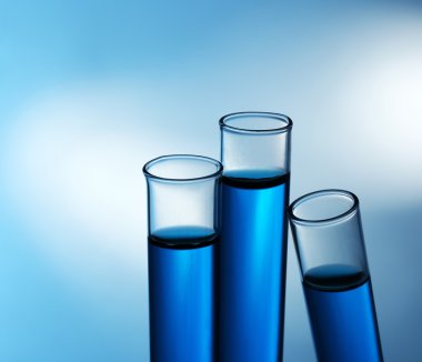 Eğimli test tüpleri gölgeler zemin üzerine mavi su ile