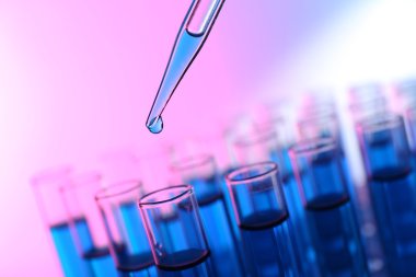 Sıvı test tüpleri arka plan parlak pembe birine ekleyerek pipet