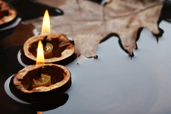 Blad och nutshells med ljus flyter i vatten — Stockfoto