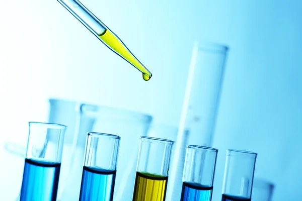 Pipette adding yellow fluid — Stock Photo, Image