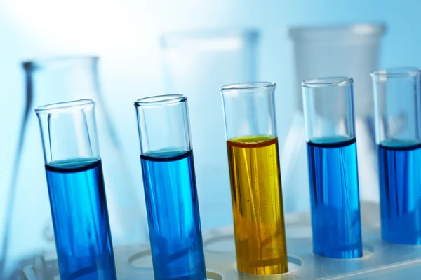 Vários tubos de ensaio cheios de fluido colorido com frascos sobre fundo claro — Fotografia de Stock