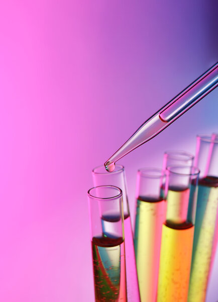 Пипетка добавляет жидкость к пробирке на розовом сияющем фоне
