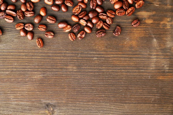 Grãos de café em fundo de madeira — Fotografia de Stock