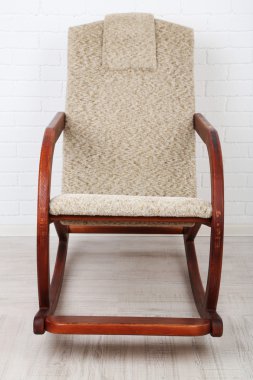 Rahat sallanan sandalye tuğla duvar arka plan yakınındaki ahşap zemin üzerinde