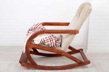 Rahat sallanan sandalye ile tuğla duvar arka plan yakınındaki ahşap zemin üzerinde halı