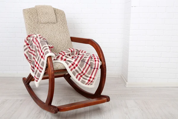 Comfortable rocking-chair with rug on wooden floor near the brick wall background — Stock Photo, Image