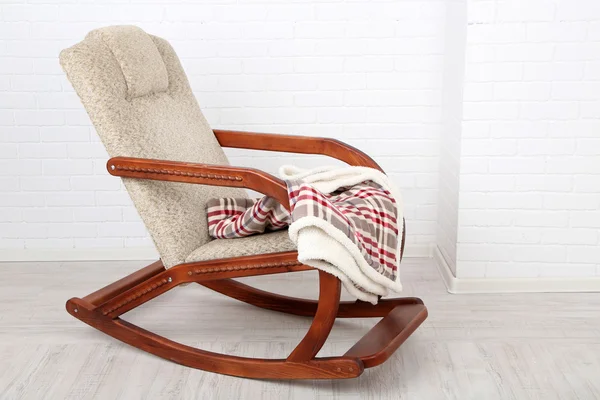Comfortabele schommelen-stoel met tapijt op houten vloer in de buurt van de bakstenen muur achtergrond — Stockfoto