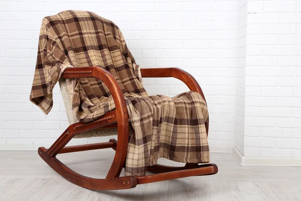 Rocking chair bedekt met plaid op houten vloer in de buurt van de bakstenen muur achtergrond — Stockfoto