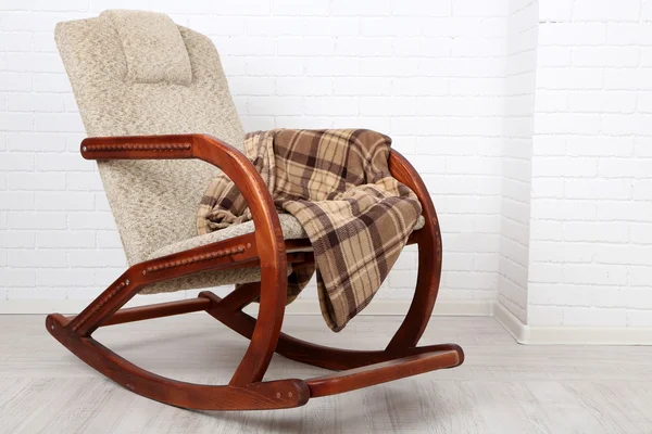 Rocking chair covered with plaid on wooden floor near the brick wall background — Stock Photo, Image