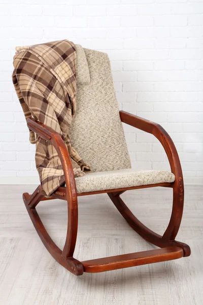 Rocking chair covered with plaid on wooden floor near the brick wall background — Stock Photo, Image