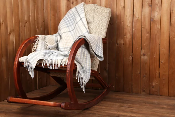 Sedia a dondolo rivestita con plaid su fondo parete in legno — Foto Stock