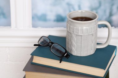 Kitaplar, kupa ve açık renkli pencere kenarında gözlük bileşimi