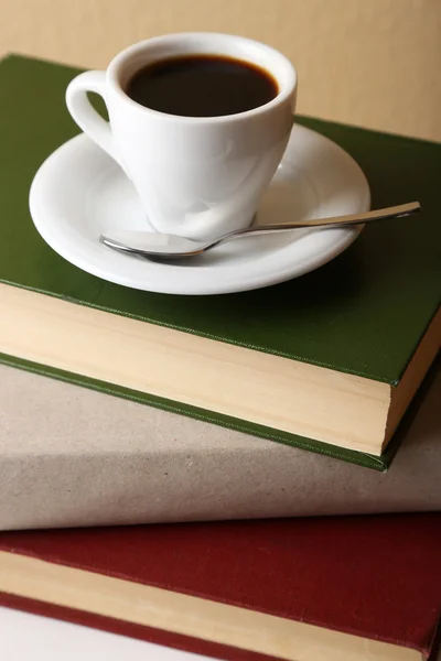 Bücherstapel mit Tasse auf Tischplatte und hellem Wandhintergrund — Stockfoto