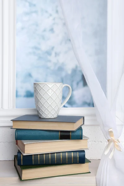 Boeken en cup op de vensterbank — Stockfoto