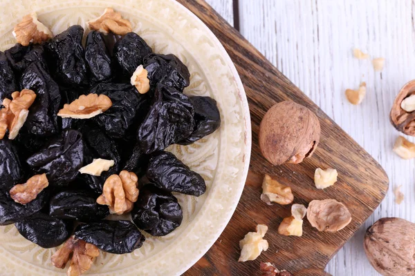 Plate of prunes and walnuts — Stock Photo, Image