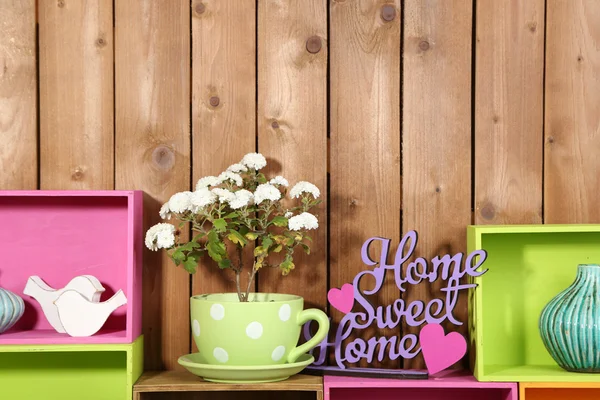 Beautiful colorful shelves with different home related objects on wooden wall background — Stock Photo, Image