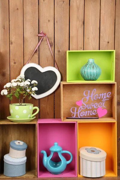 Красивые красочные полки с различными предметами домашнего обихода на фоне деревянной стены — стоковое фото