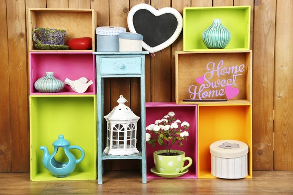 Beautiful colorful shelves with different home related objects on wooden wall background — Stock Photo, Image