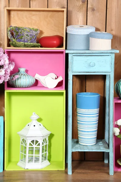 Prateleiras coloridas bonitas com diferentes objetos relacionados com a casa no fundo da parede de madeira — Fotografia de Stock