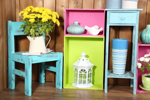 Beautiful colorful shelves with different home related objects on wooden wall background — Stock Photo, Image