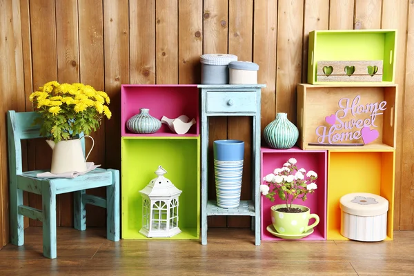 Beautiful colorful shelves with different home related objects on wooden wall background — Stock Photo, Image