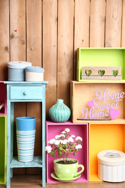 Belles étagères colorées avec différents objets liés à la maison sur fond de mur en bois — Photo