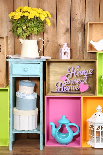 Prachtige kleurrijke planken met verschillende huis verwante objecten op houten muur achtergrond — Stockfoto