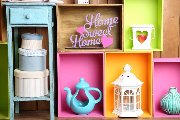 Beautiful colorful shelves with different home related objects on wooden wall background — Stock Photo, Image