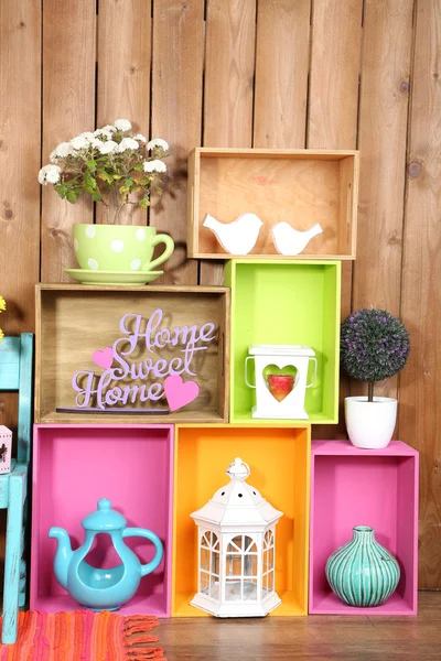 Beautiful colorful shelves with different home related objects on wooden wall background — Stock Photo, Image