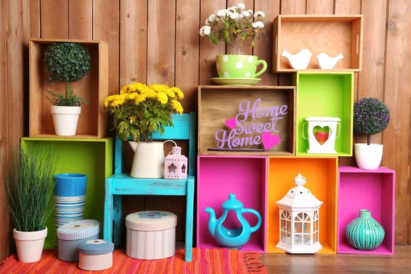Vackra färgglada hyllor med olika hem relaterade objekt på trävägg bakgrund — Stockfoto