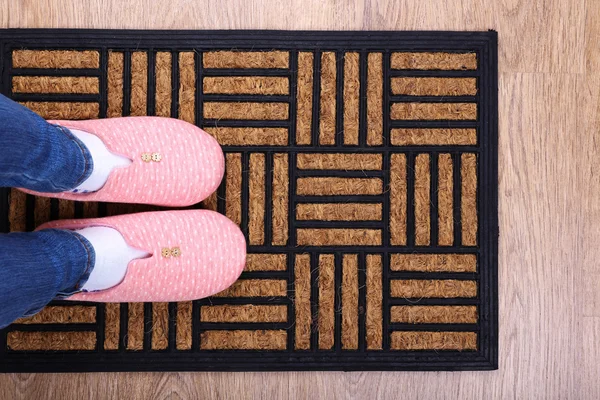 Girl in home slippers on brown carpet on floor close-up — Stock Photo, Image