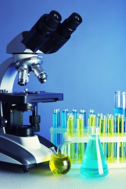 Mikroskop ve masaya renk arka plan üzerinde test tüpleri