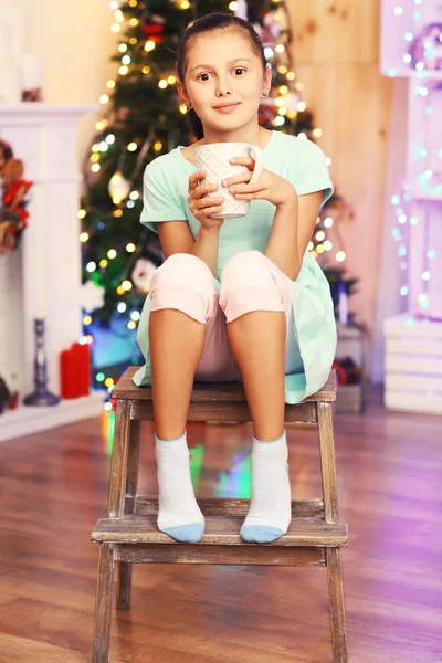 Cute little girl with milk near Christmas tree — Stock Photo, Image