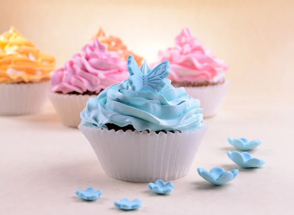 Deliciosos cupcakes no fundo bege — Fotografia de Stock