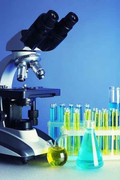 Mikroskop ve masaya renk arka plan üzerinde test tüpleri
