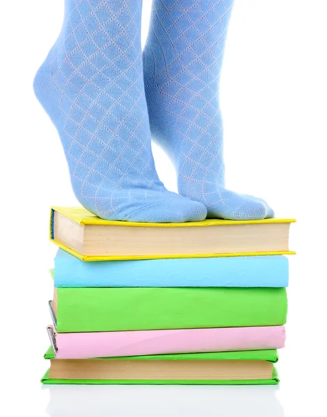 Girl in colorful socks standing on pile of books isolated on white — Stock Photo, Image