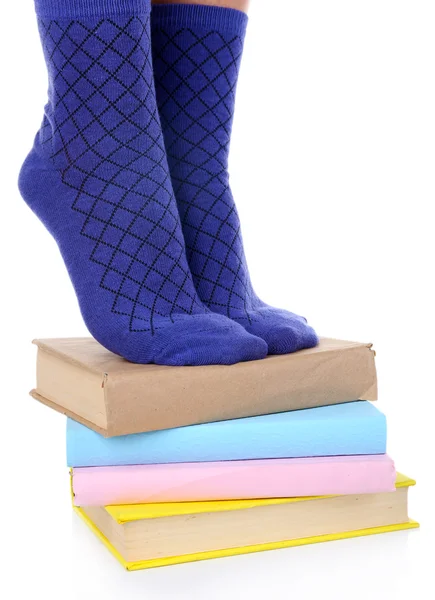 Girl in colorful socks standing on pile of books isolated on white — Stock Photo, Image