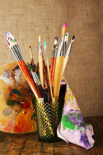 Paint brushes with paints and palette on beige background — Stock Photo, Image